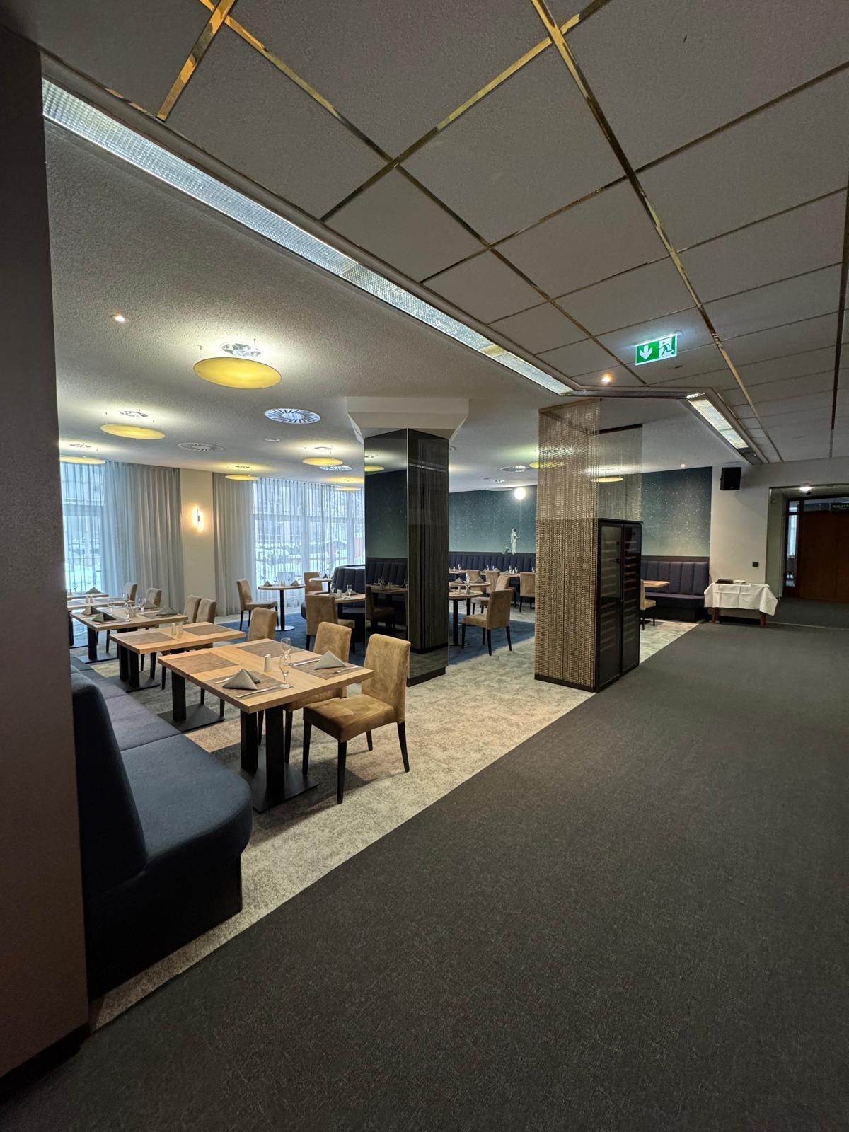 Modernes Restaurant mit gedeckten Tischen, beigen Stühlen und großen Fenstern