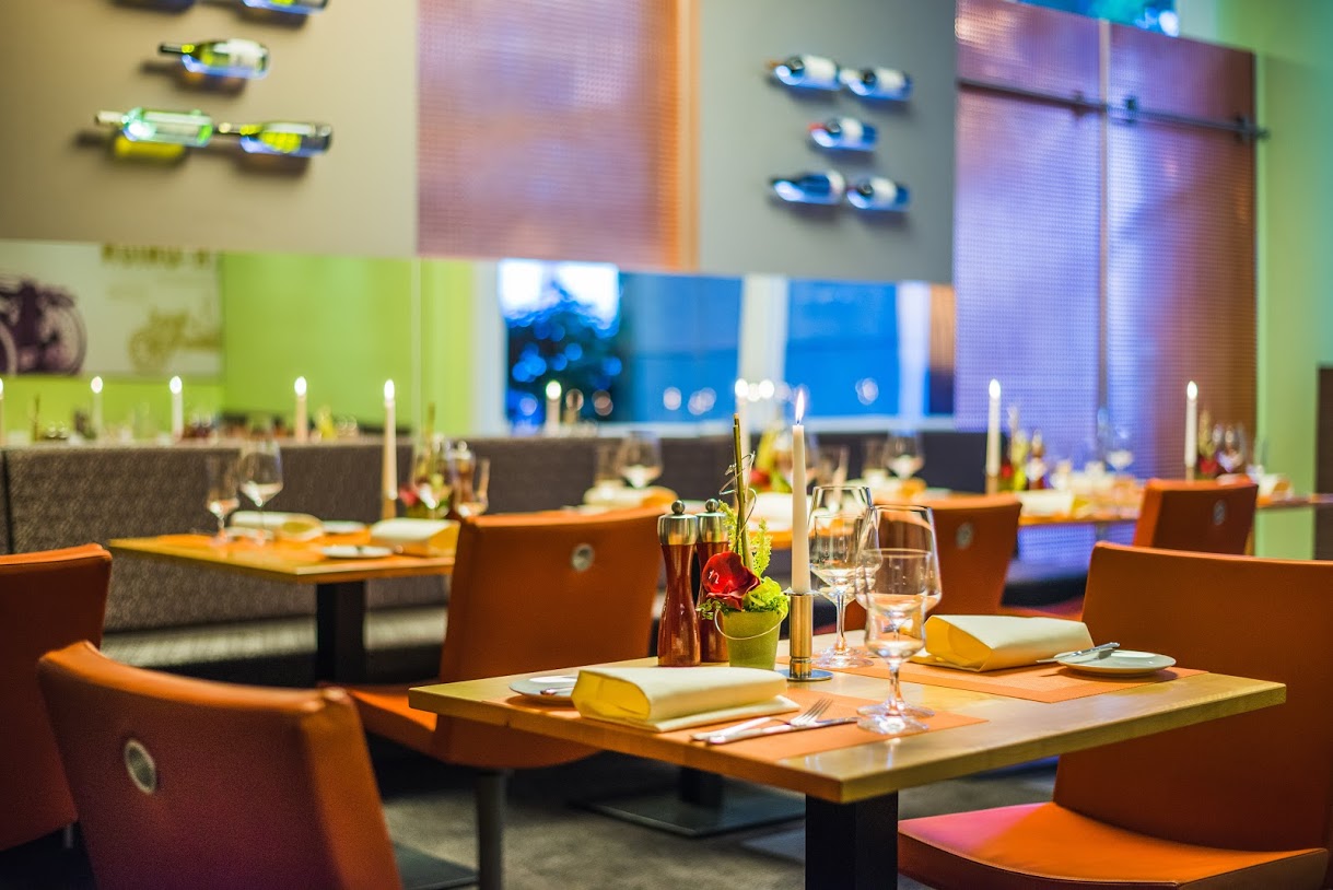 Schön gedeckter Tisch in einem modernen Restaurant mit orangefarbenen Stühlen und Kerzenlicht